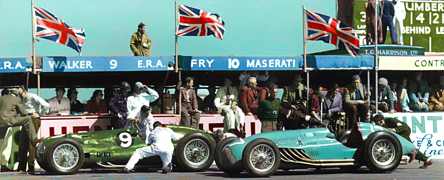 Historic British Racing Green and French Racing Blue cars in the pit lane.